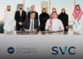 A group photo showing the team from SVC and General Atlantic after signing an investment agreement, with men in traditional Saudi and Emirati attire and women in modest clothing, seated at a long table with the SVC and General Atlantic logos displayed.